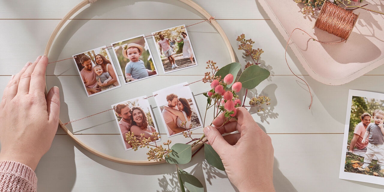 Una mano decora una cornice con fiori e foto.