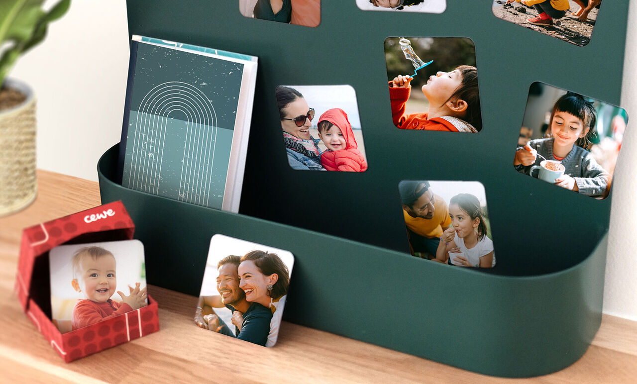 Una parete con foto colorate, tra cui un CEWE fotolibro e una piccola scatola regalo.