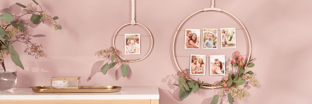 Meravigliosa decorazione murale con foto in anelli dorati e piante fresche.
