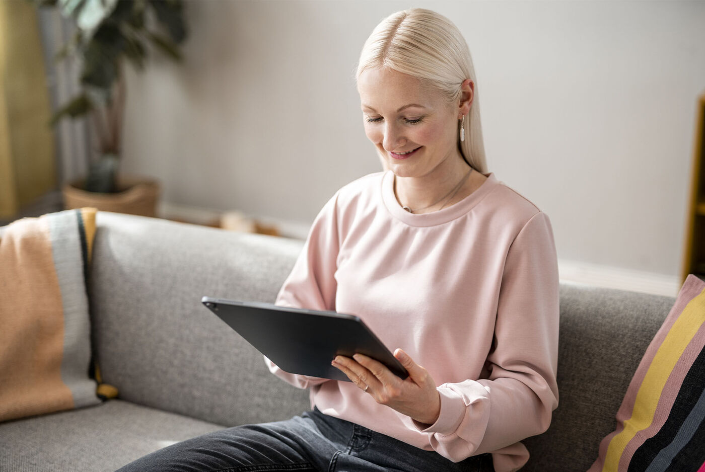 Persona con un tablet sul divano, circondata da un'atmosfera accogliente.