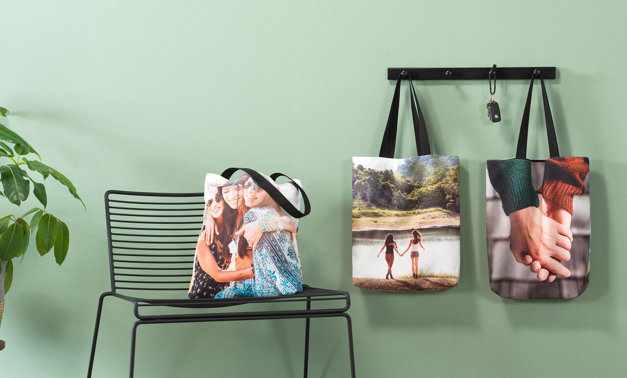 Tre borse decorative con foto personali su un muro e una sedia in una stanza moderna.
