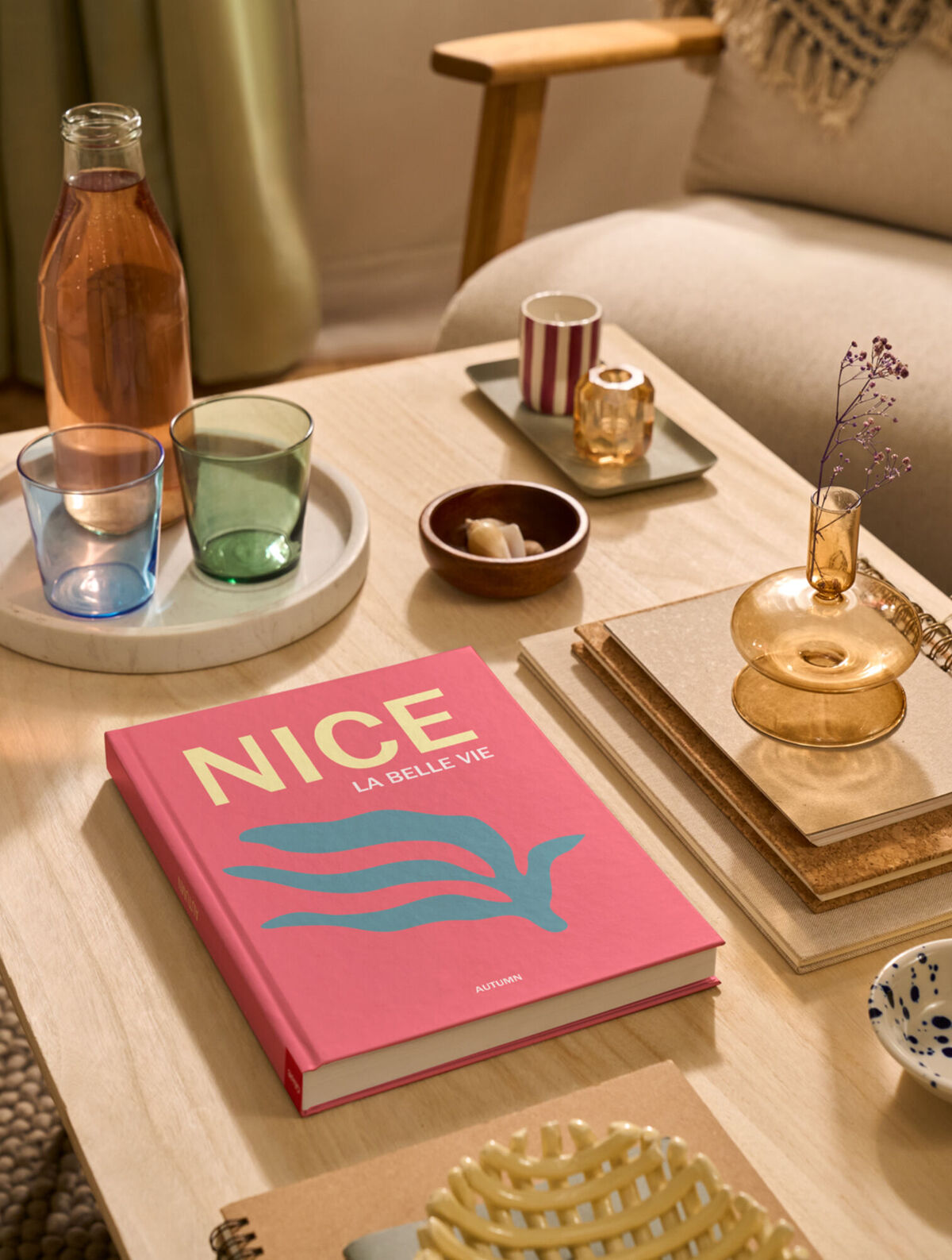 Un FOTOLIBRO Cewe è appoggiato su un tavolino da caffè. La copertina è rosa e riporta la parola "Nice".