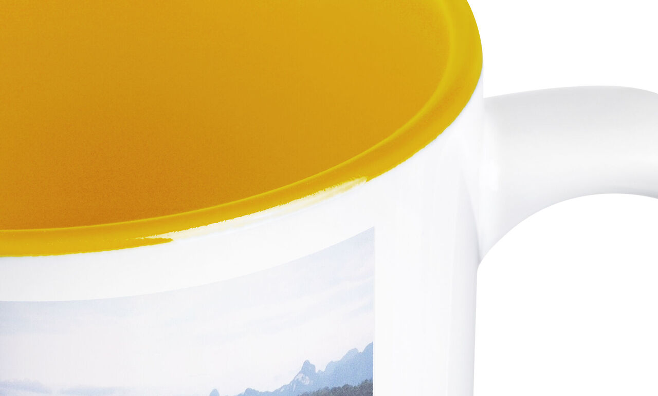 Tazza beige con bordo giallo e motivo di montagna.