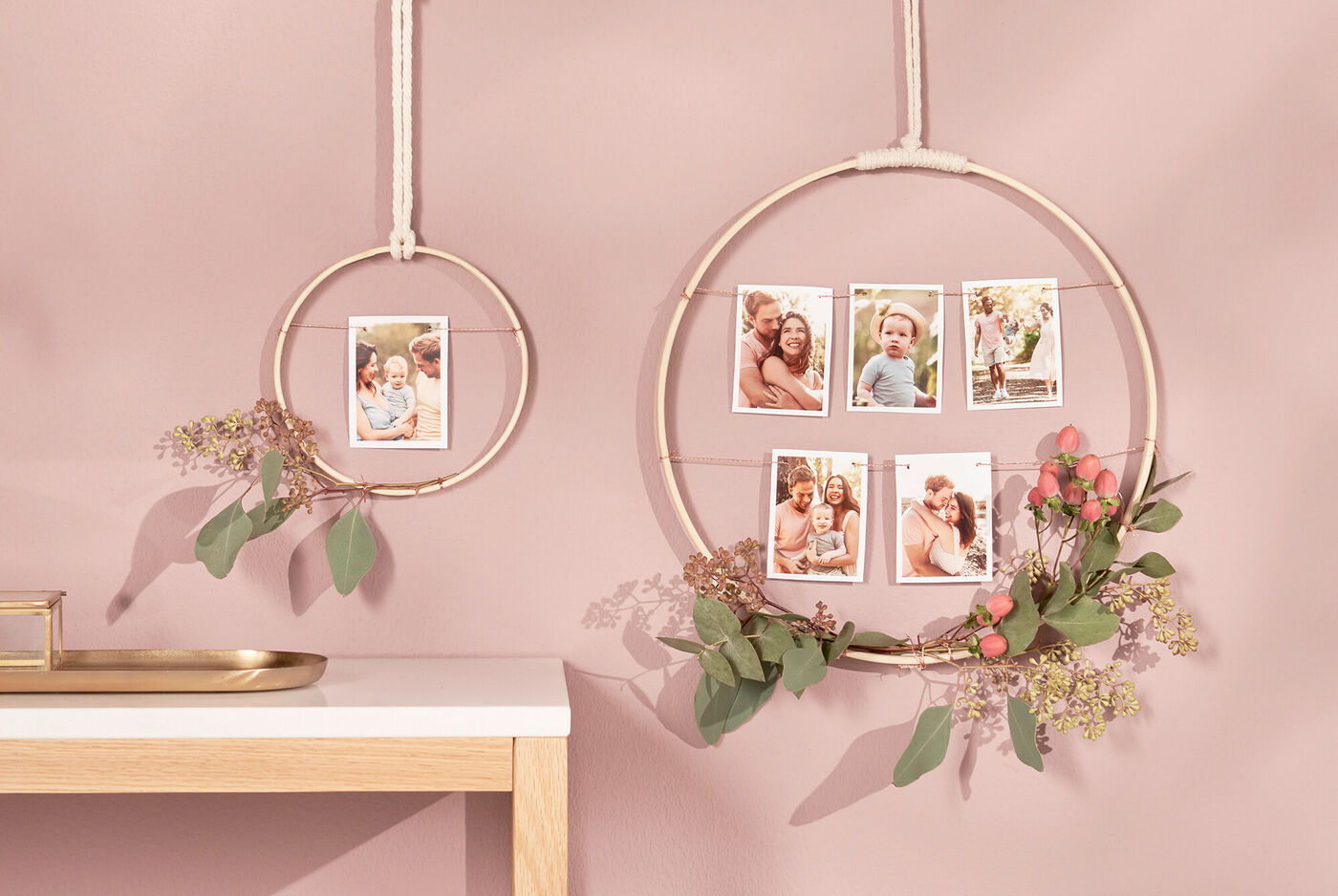 Due cornici rotonde con foto di momenti felici di famiglia e fiori freschi su una parete rosa