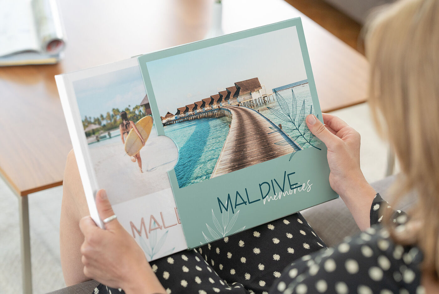 Una persona sfoglia un libro fotografico CEWE con ricordi delle Maldive.