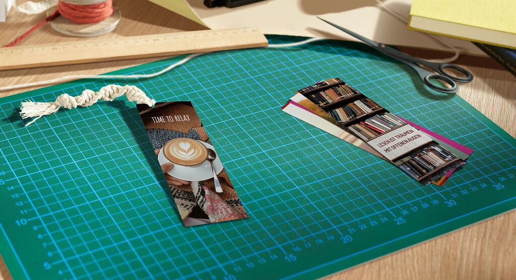 Su un tavolo da lavoro sono appoggiati due segnalibri personalizzati con foto a tema hobby.