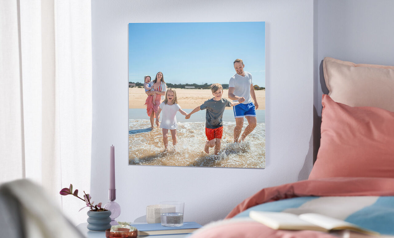 Una famiglia felice gioca in acqua sulla spiaggia. Due adulti e due bambini si tengono per mano. La luce del sole splende su di loro.