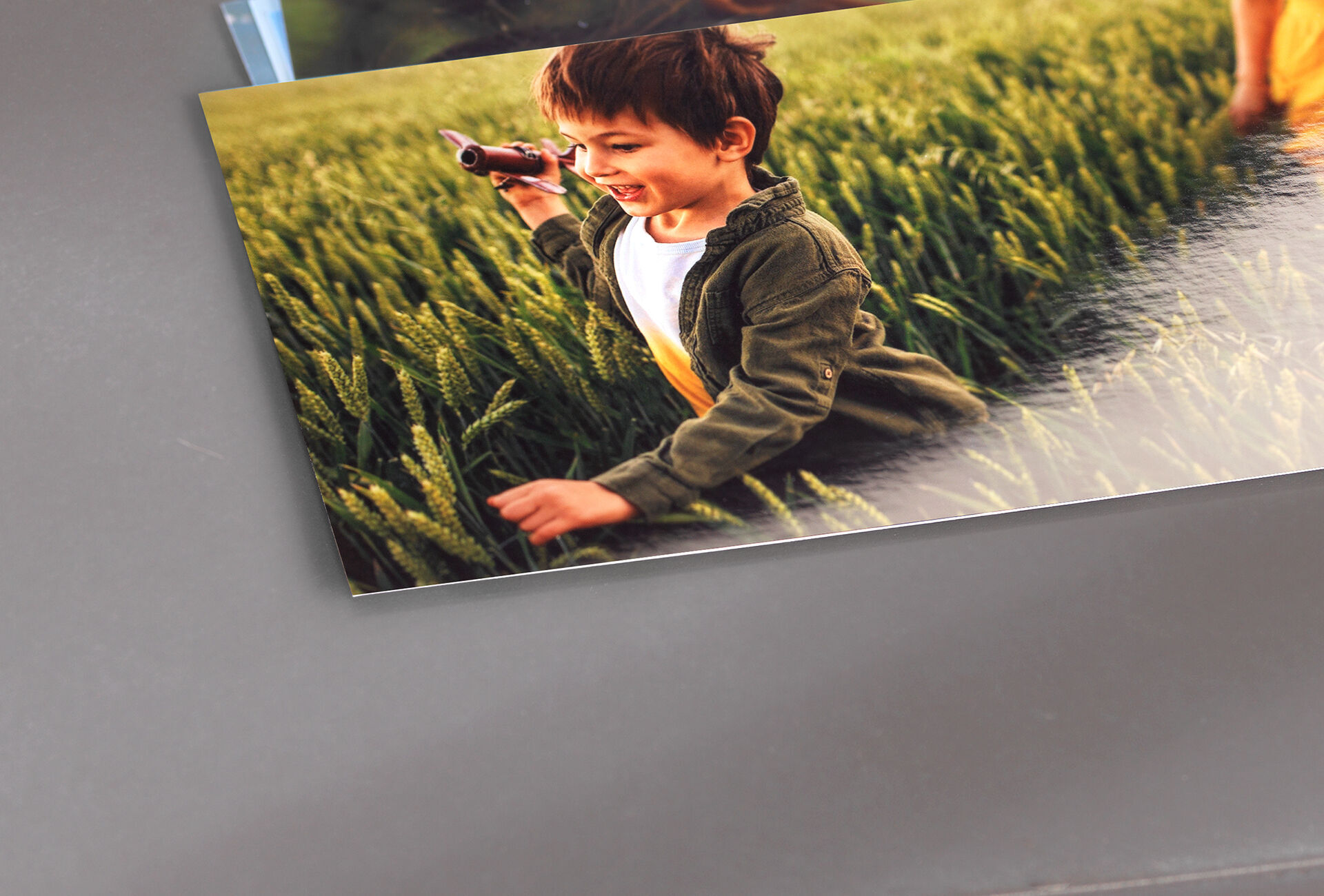 Un bambino in un campo cerca qualcosa con una macchina fotografica giocattolo.